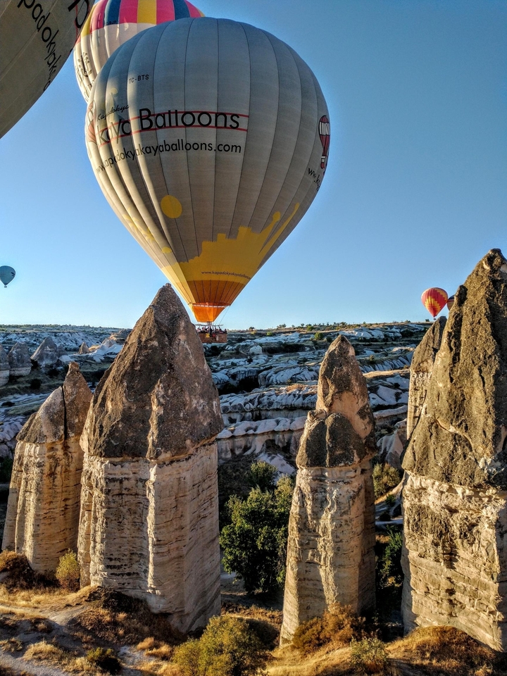 Montgolfière volant à basse altitude au-dessus de formations rocheuses uniques.