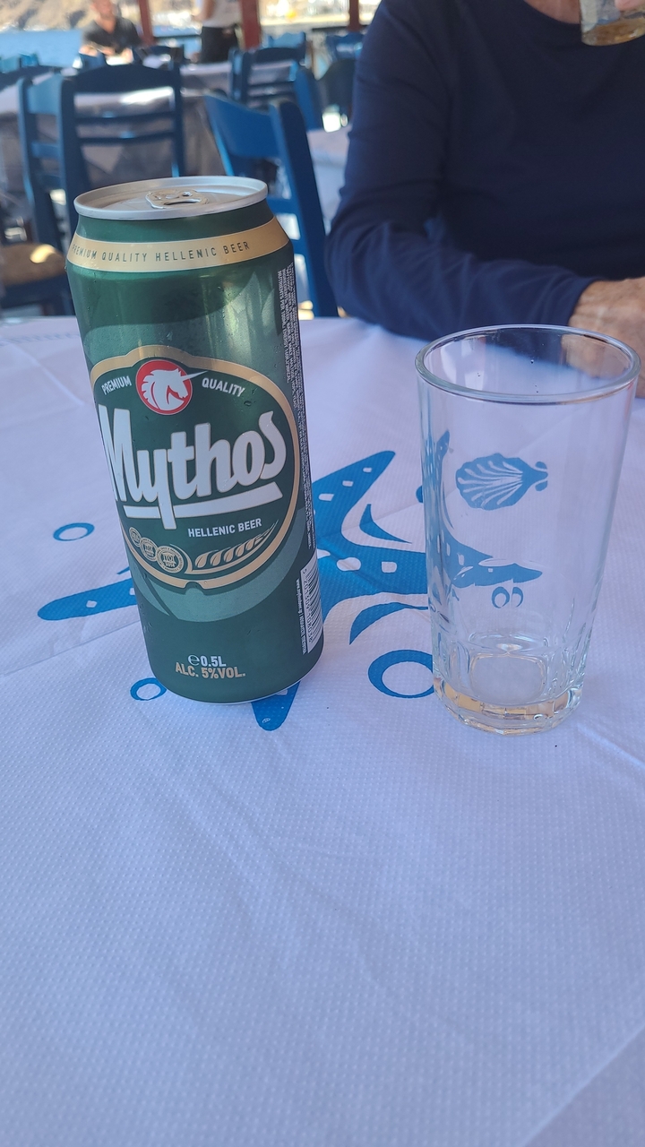 Canette de bière grecque sur une table avec un verre.