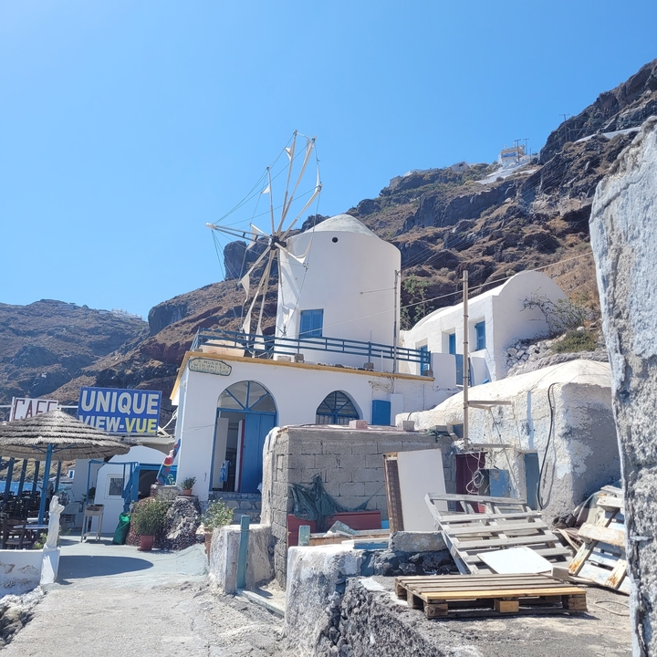 Moulin à vent sur une colline avec des bâtiments à proximité.