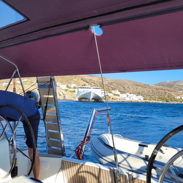 Ferry vu depuis un voilier avec un village côtier à proximité.