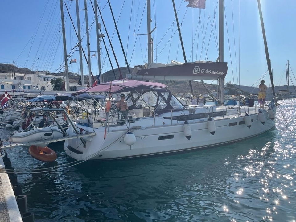 Voilier amarré dans un port de plaisance avec des montagnes en arrière-plan.