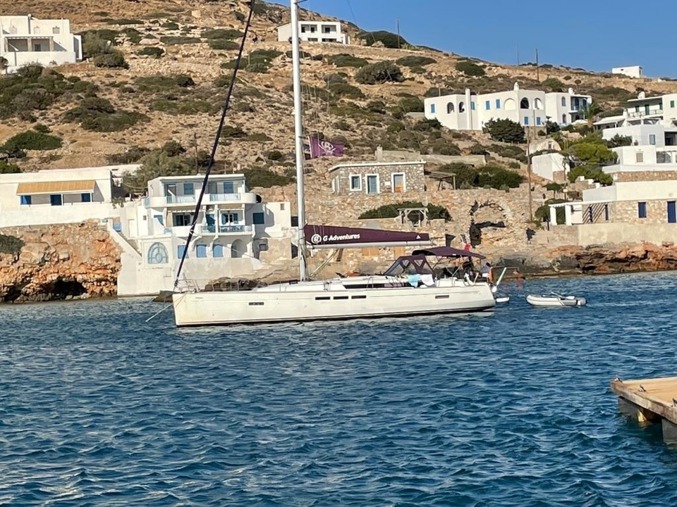 Voilier amarré près d'un rivage rocheux avec des bâtiments blancs.