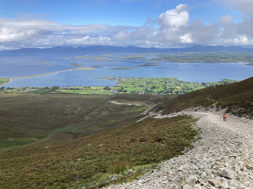 Mountainous path leading down to a lake and landscape with islands.