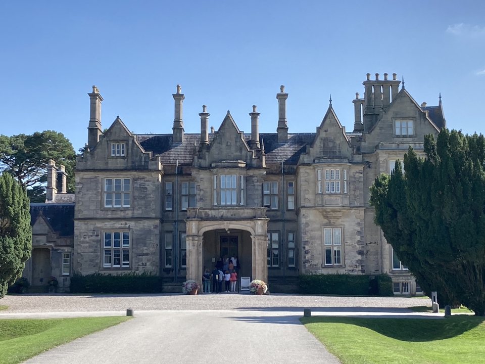 Classic manor house with a group of people at the entrance.