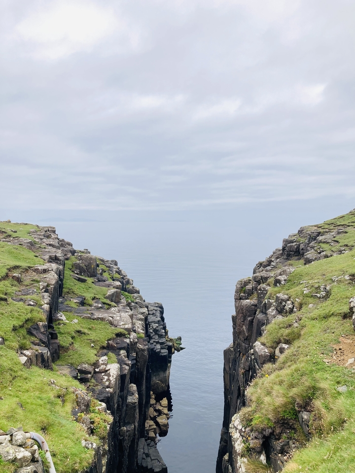 Vue à travers une brèche rocheuse vers la mer.