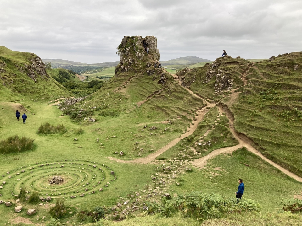 Colline rocheuse avec des gens qui explorent et spirale de pierre au premier plan.