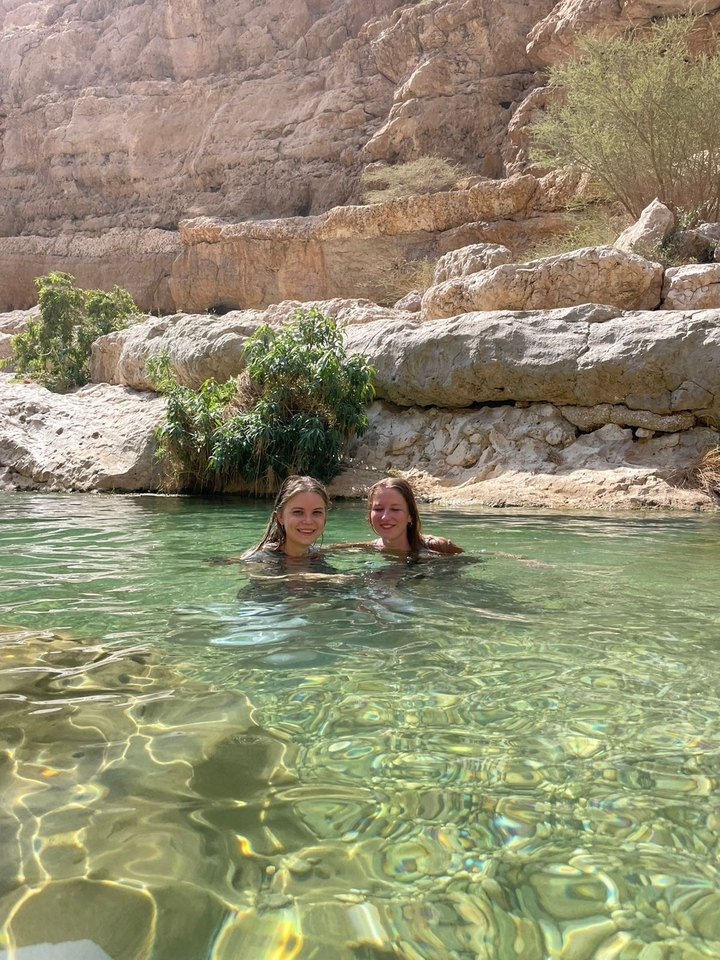 Deux femmes qui nagent dans une piscine naturelle entourée d'un terrain rocheux.