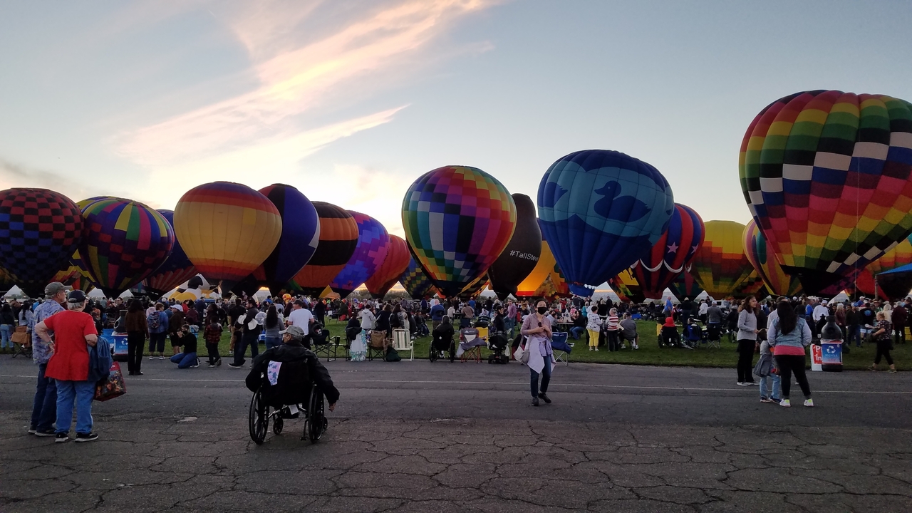 Des montgolfières colorées dans un champ avec une foule.