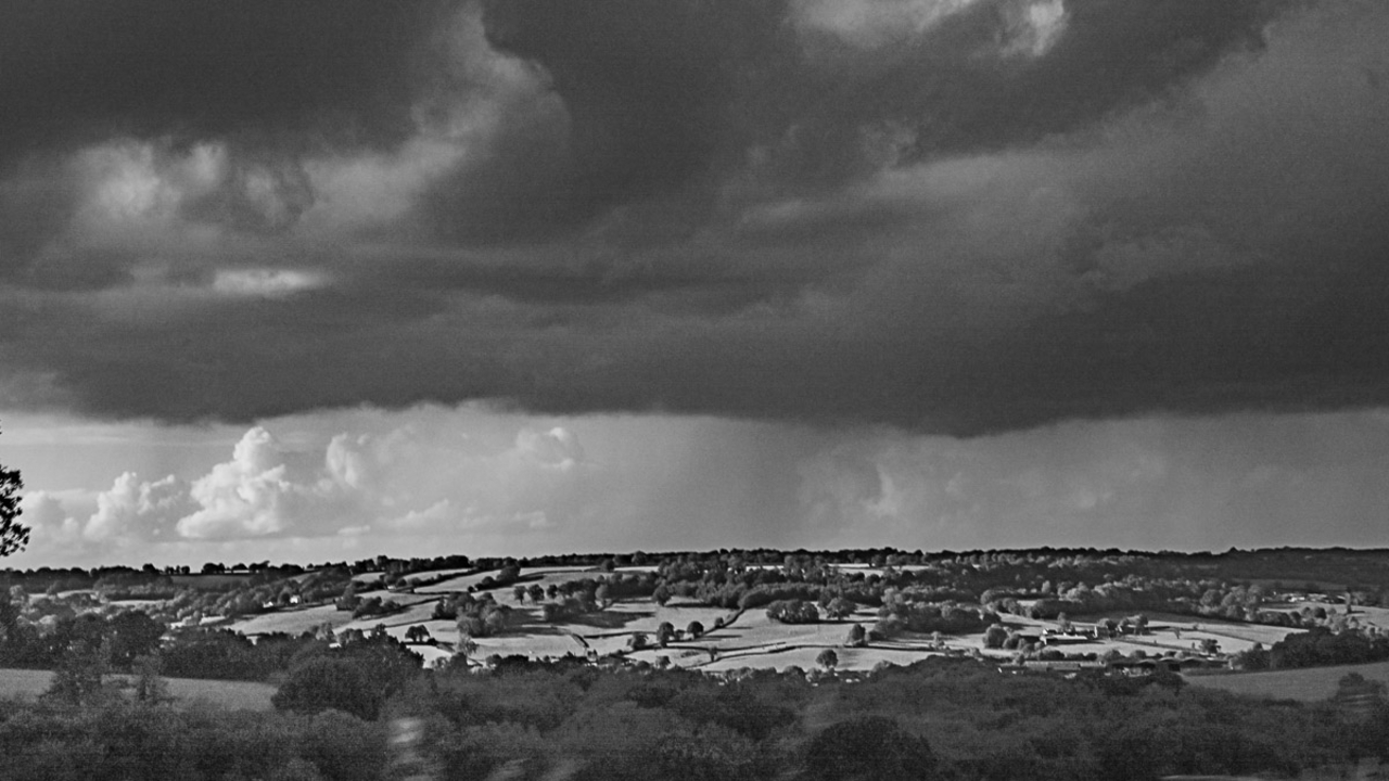 Paysage vallonné avec des nuages dramatiques au-dessus.
