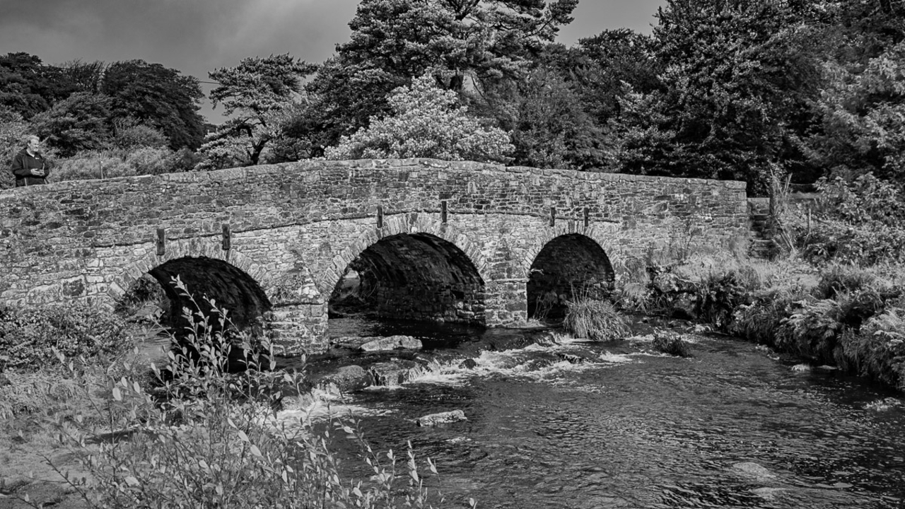 Pont en arc de pierre au-dessus d'un ruisseau qui coule.