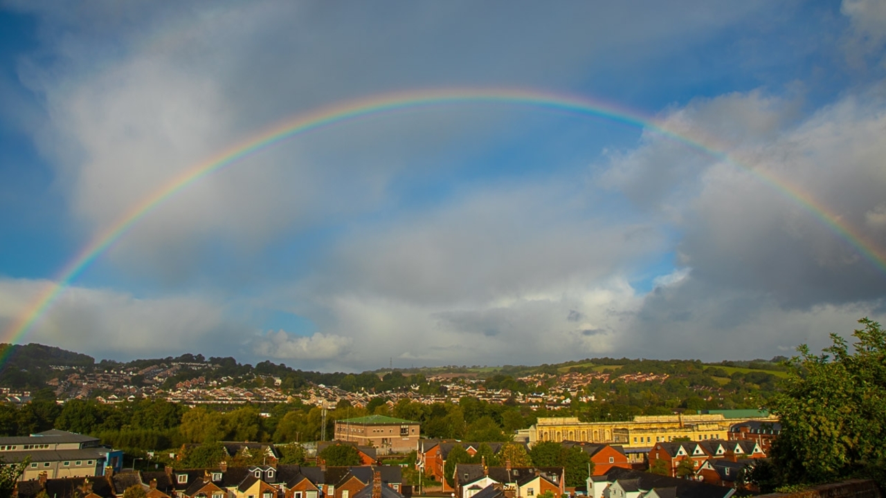 Un arc-en-ciel au-dessus d'un paysage urbain sous un ciel qui se dégage.