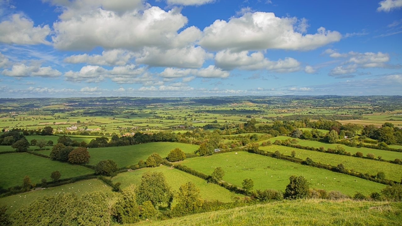 Vue étendue d'un paysage rural verdoyant avec des nuages épars.