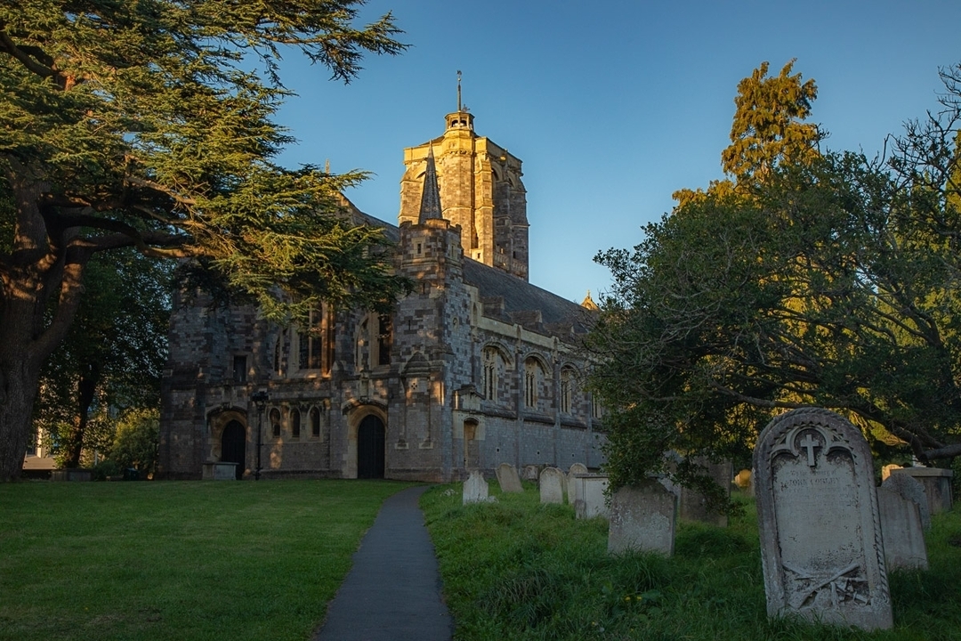 Église historique en pierre avec cimetière au coucher du soleil.