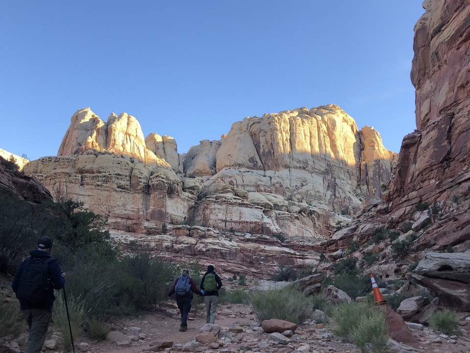 Des randonneurs marchant à travers un canyon aux falaises imposantes.