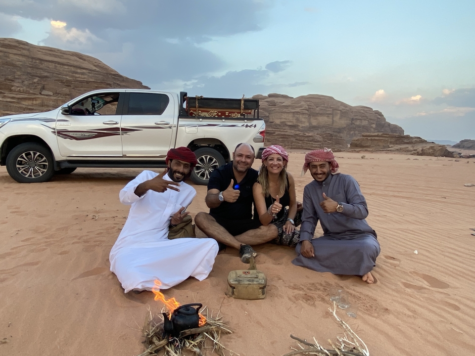 Des personnes prenant la pose avec une camionnette dans un paysage désertique.