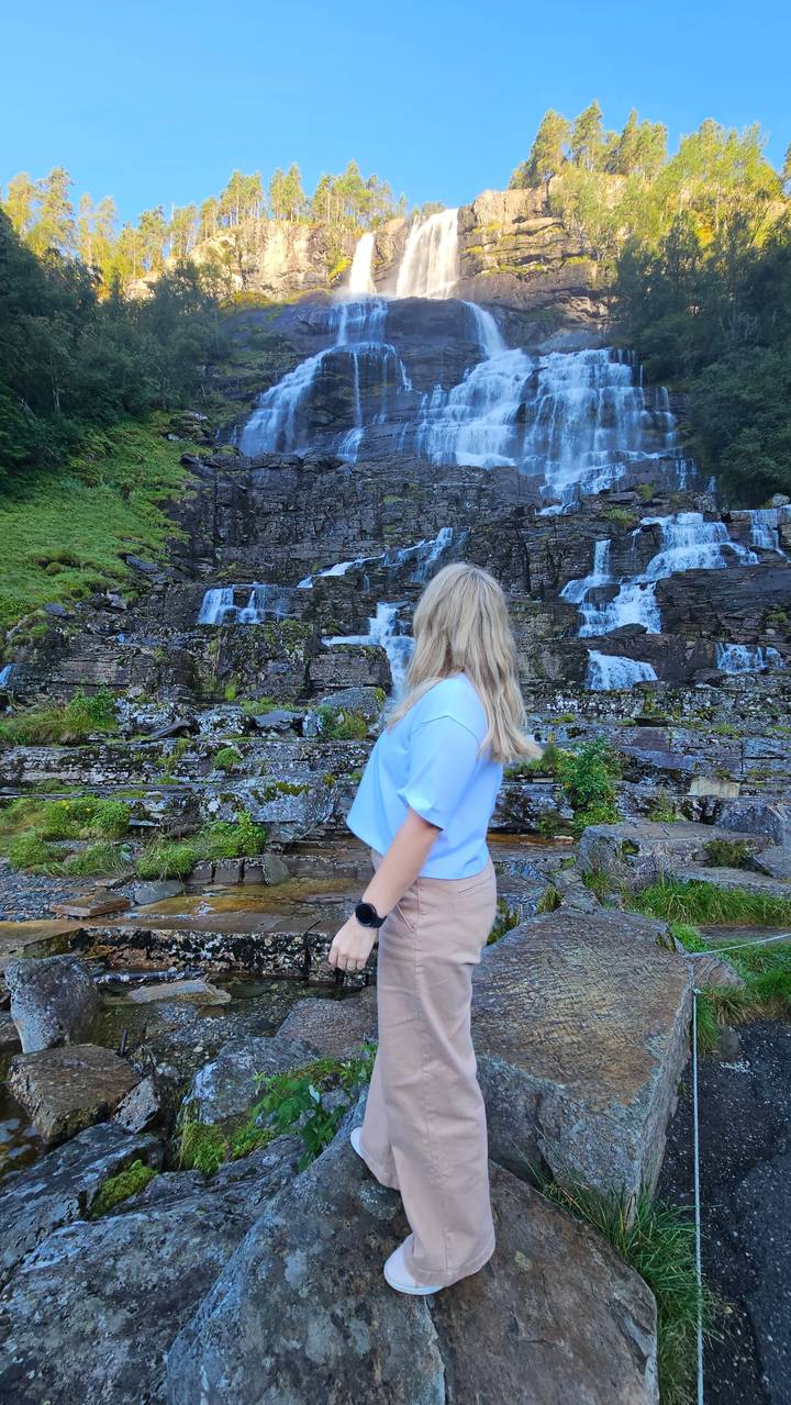 Person standing on rocks by a waterfall.