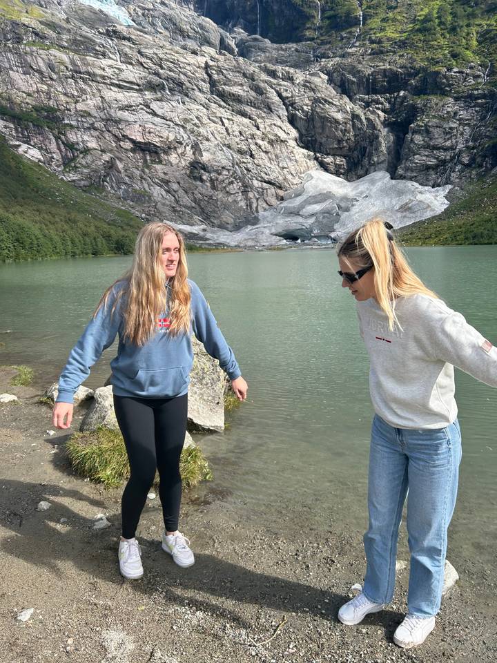 Two people posing near a lake and glacier.