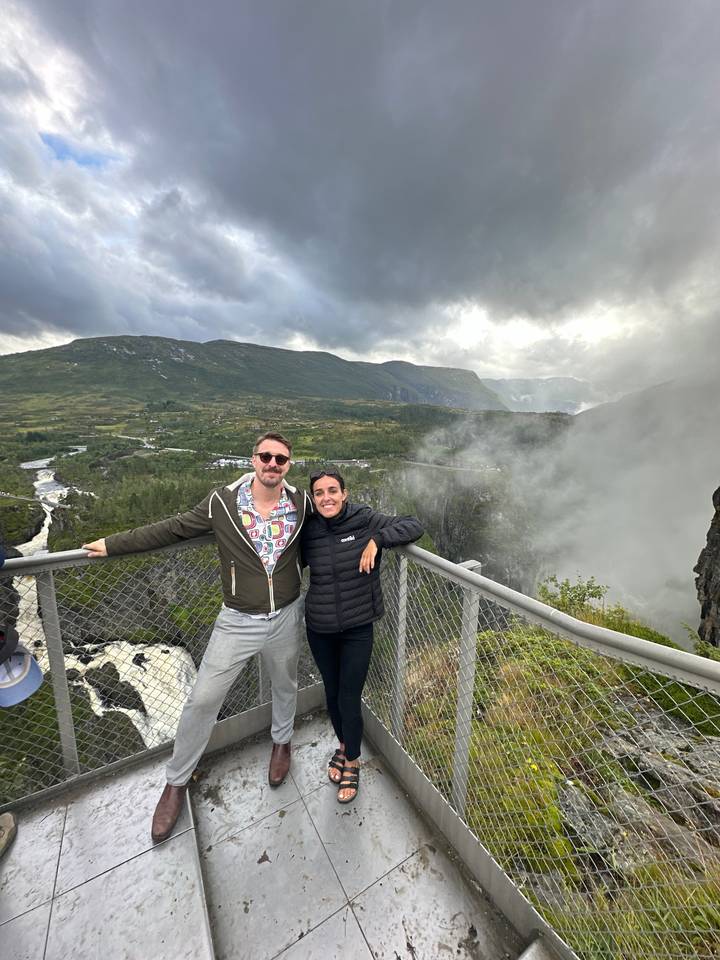 Two people posing on a viewing platform with scenic views.