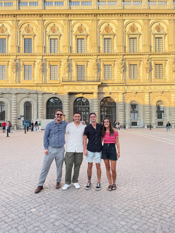 Group of people posing in front of a large historic building.