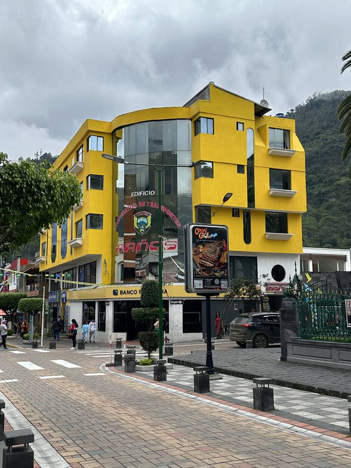 People walking on a street in front of a yellow building.