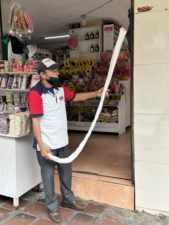 Man holding a long, twisted candy in a shop.