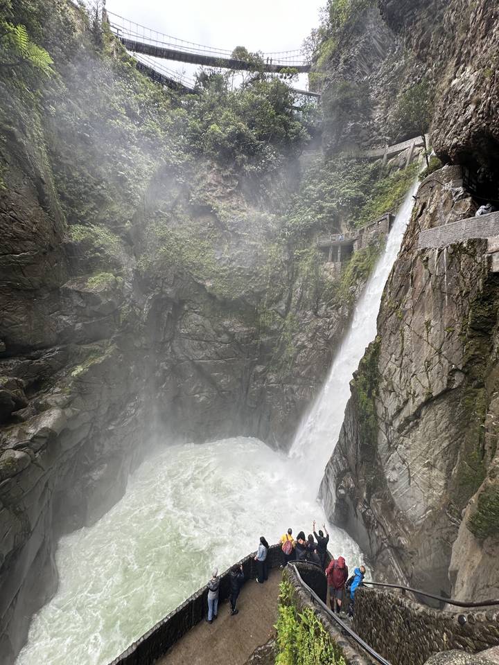 Powerful waterfall with mist and tourists viewing.