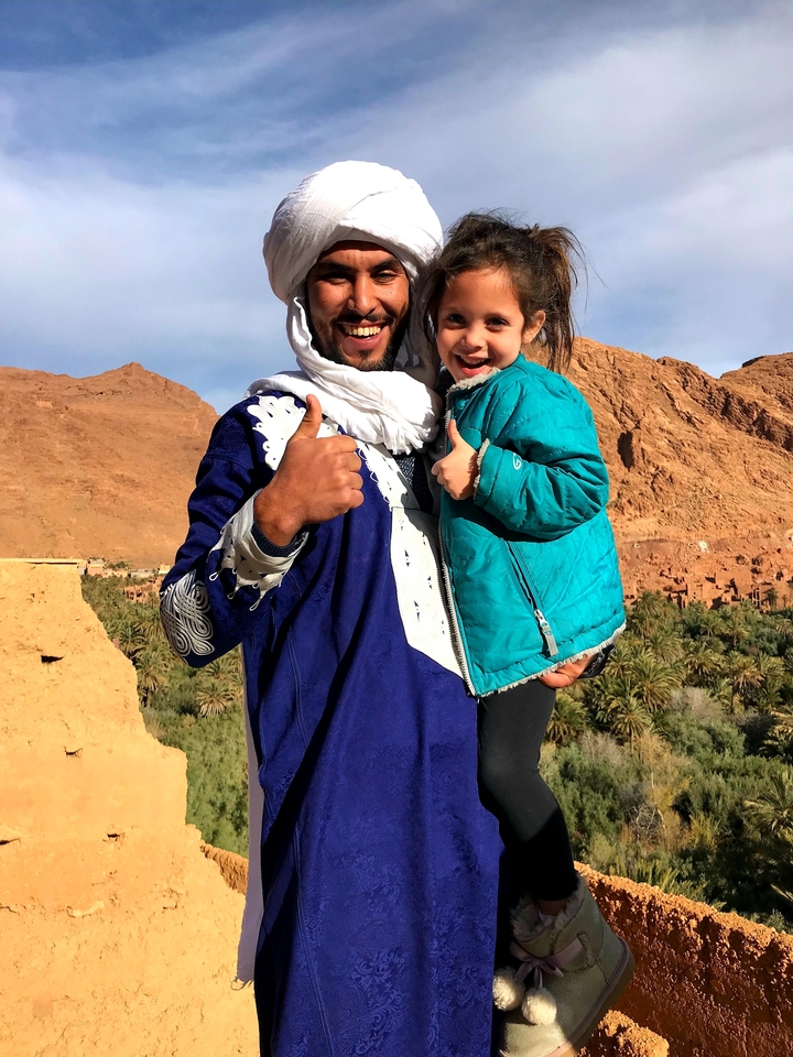 Un homme et un enfant en vêtements traditionnels souriants à la caméra