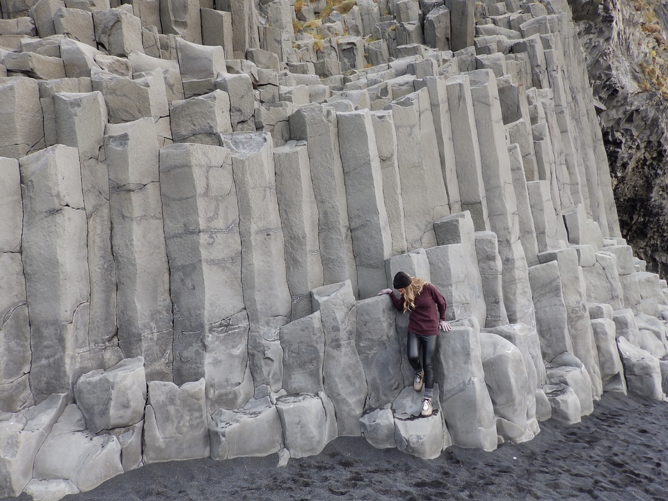 Personne escaladant des colonnes de basalte près de la côte.