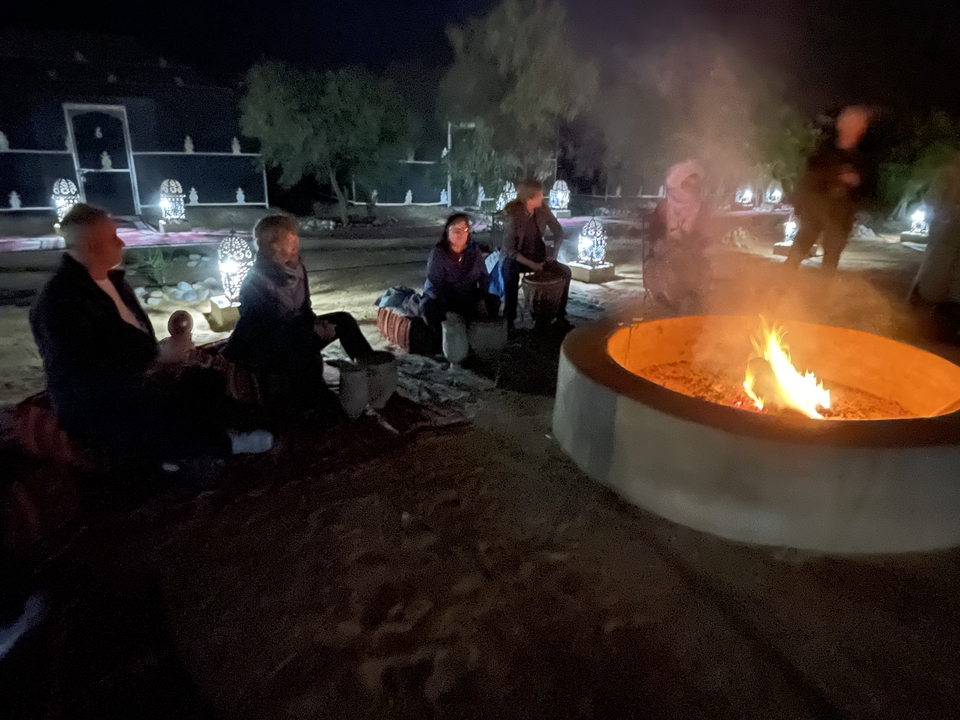 Des gens assis autour d'un feu de camp dans l'obscurité.