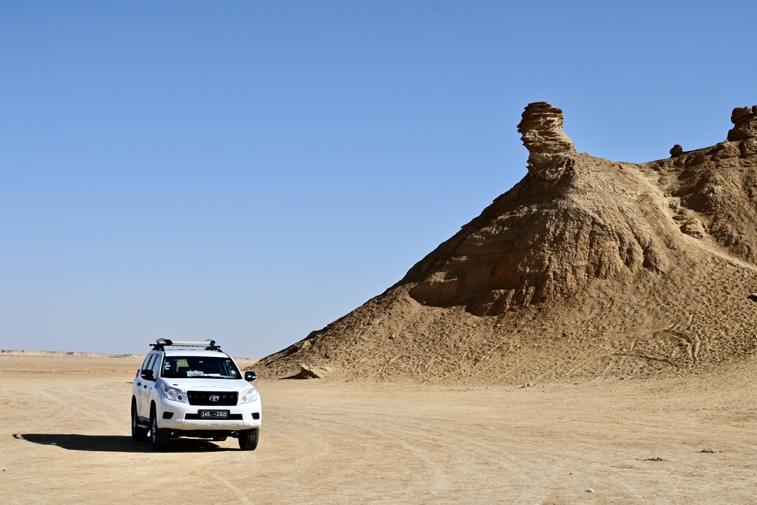 VUS garé dans un désert avec une formation rocheuse unique.
