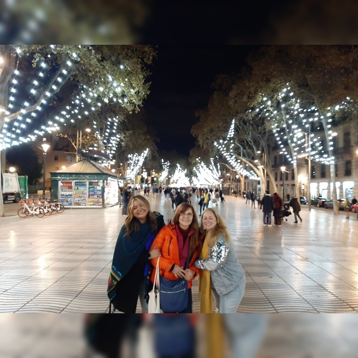 Des femmes souriantes la nuit avec les lumières de la ville en arrière-plan.