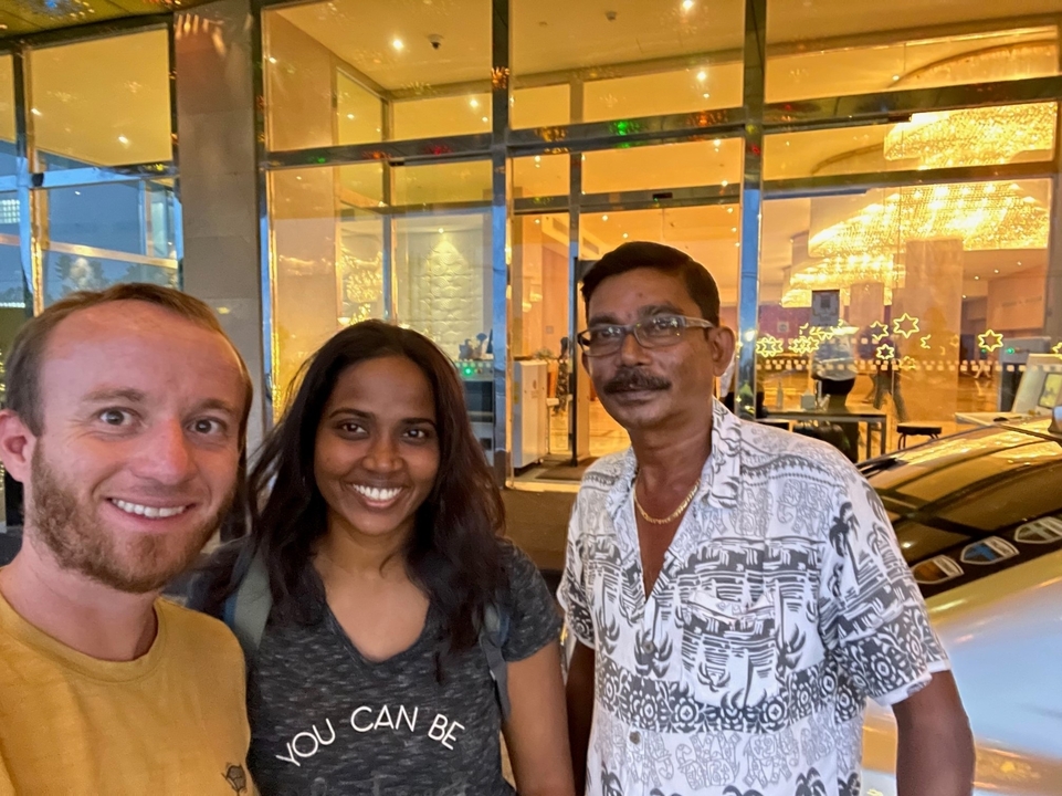 Trois personnes souriant devant un bâtiment de verre.