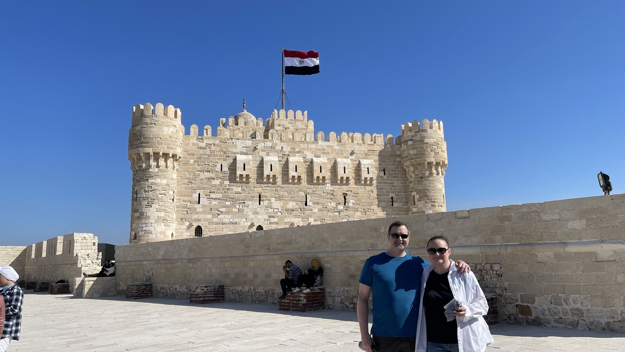 Des gens posent devant une forteresse avec un drapeau.
