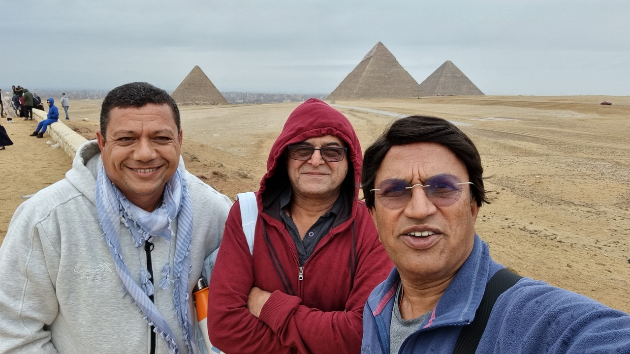 Selfie avec trois personnes et des pyramides en arrière-plan.