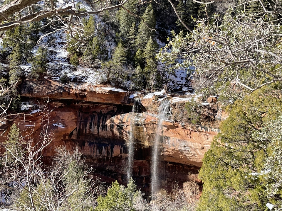 Cascade tombant d'une falaise dans un paysage hivernal.