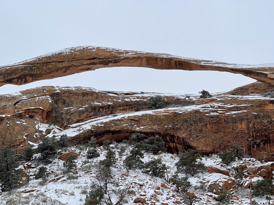 Arche enneigée dans un paysage désertique rocheux.