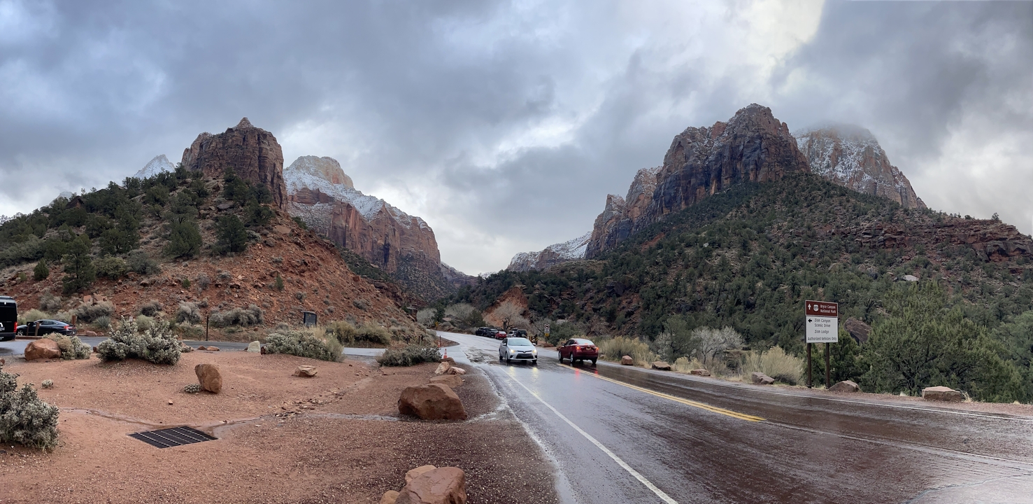 Véhicules sur une route panoramique bordée de montagnes enneigées.