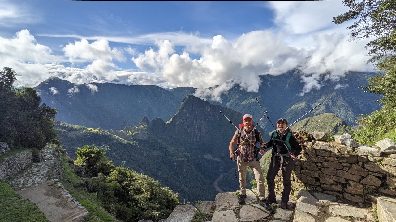 Deux randonneurs avec des bâtons de randonnée contemplant les montagnes.