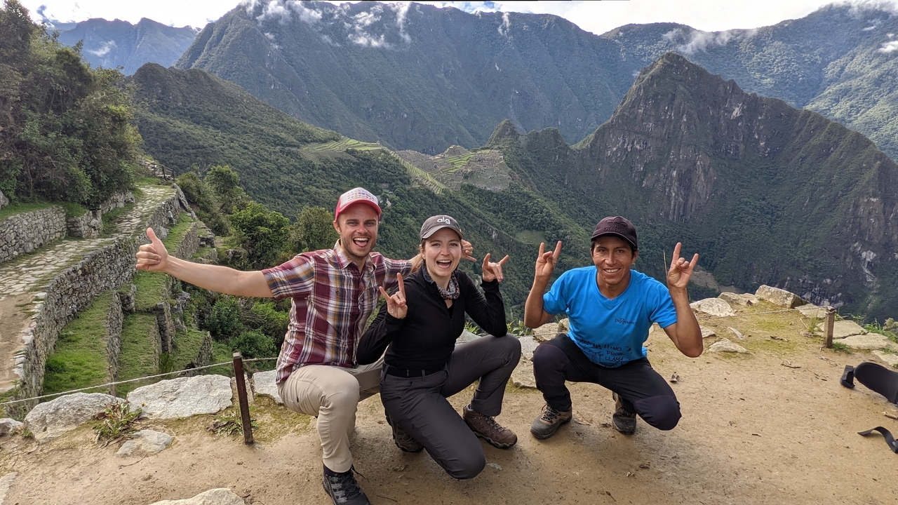 Groupe de trois personnes posant avec des collines en arrière-plan.