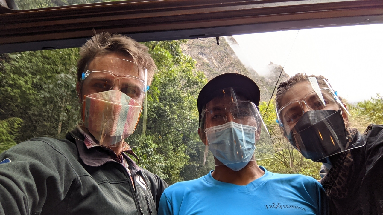 Trois personnes portant des masques faciaux dans un cadre tropical.