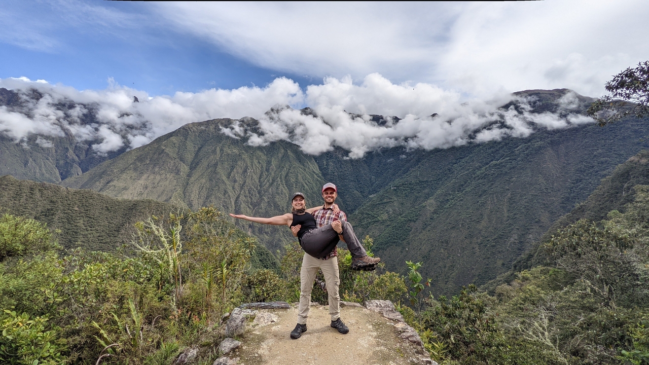 Homme portant une femme dans un paysage de montagne.
