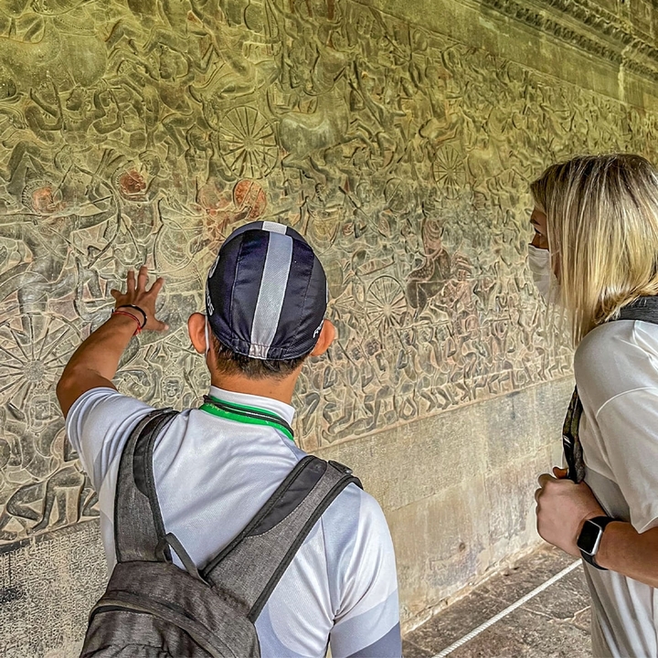 Deux personnes observant des gravures murales anciennes.