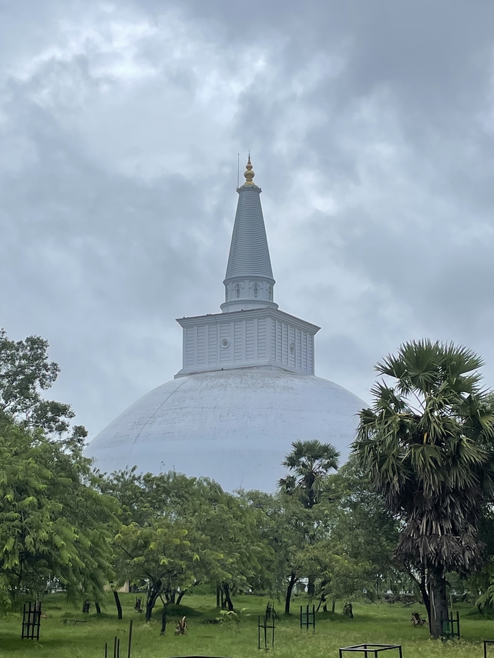 Structure blanche à dôme avec flèche contre un ciel nuageux.