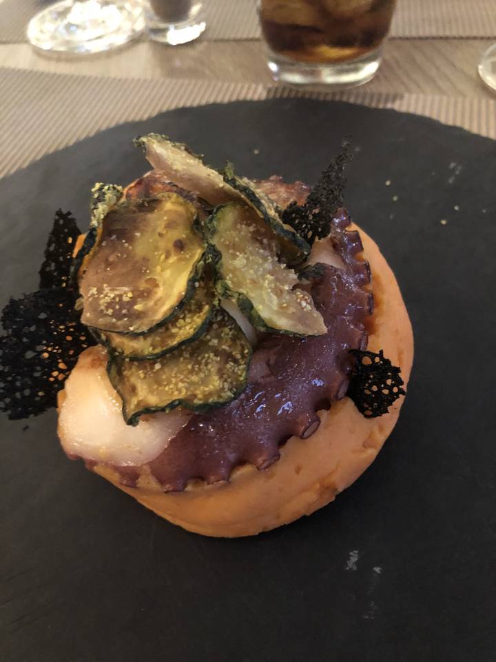 Plat gastronomique servi dans une assiette sombre.