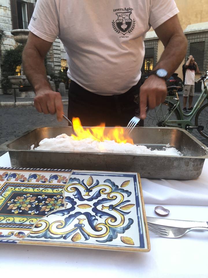 Personne préparant un plat avec du feu dans un restaurant.