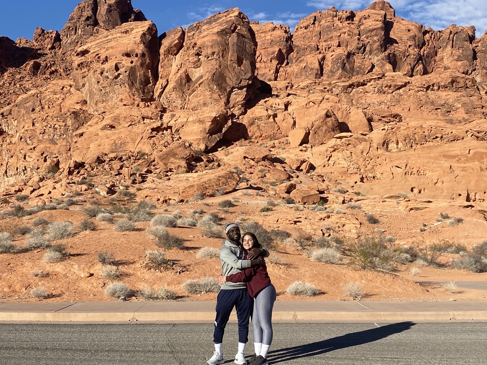 Couple s'embrassant avec un paysage de rochers désertiques en arrière-plan.