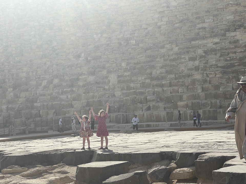 Des enfants et des personnes se tenant près d'une grande structure en pierre.