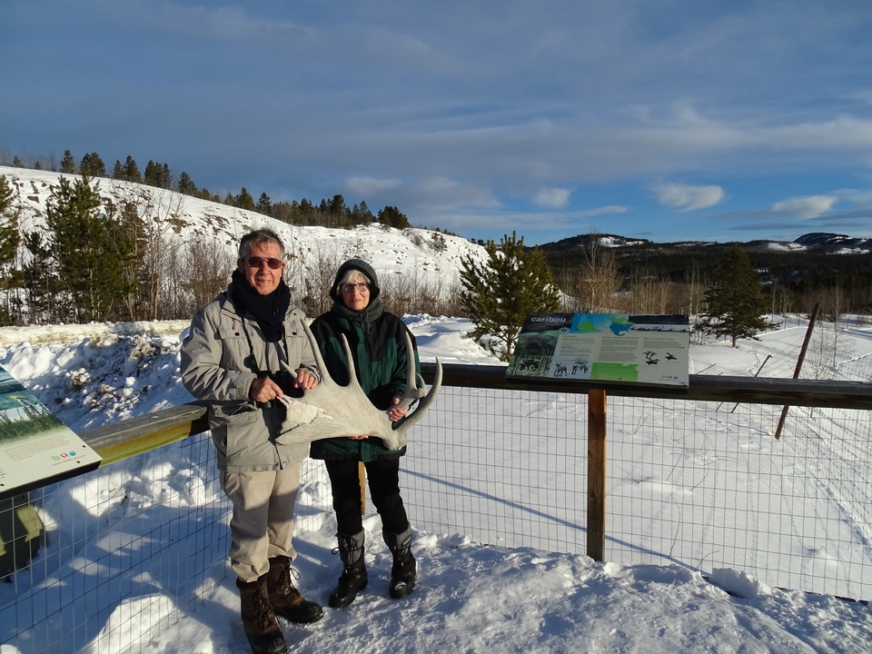 Des gens qui posent avec un grand bois de cerf et un paysage enneigé pittoresque en arrière-plan.
