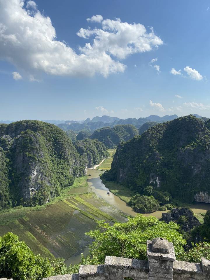 Vue panoramique d'une vallée fluviale avec une végétation luxuriante et des affleurements rocheux.