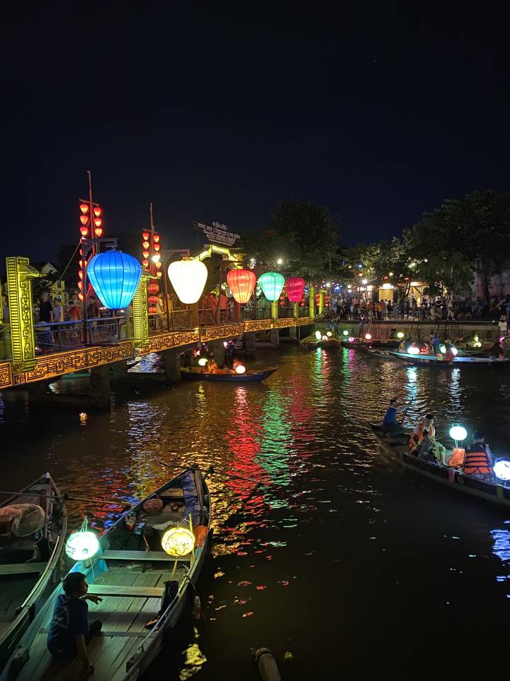 Un marché de nuit avec des lanternes illuminées se reflétant sur l'eau.
